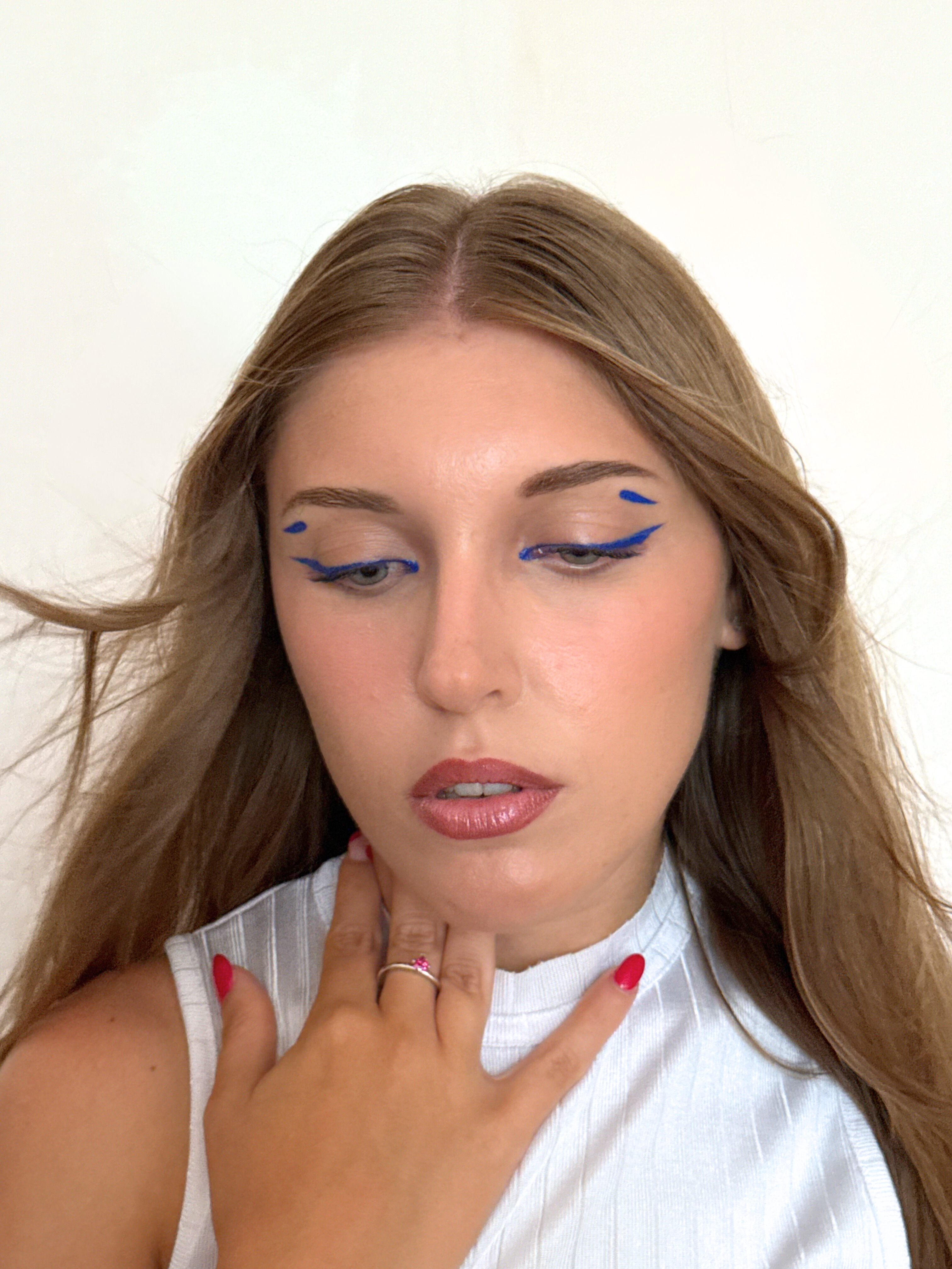 Electric blue graphic eyeliner that gives intensity to the gaze, paired with rosy lips.